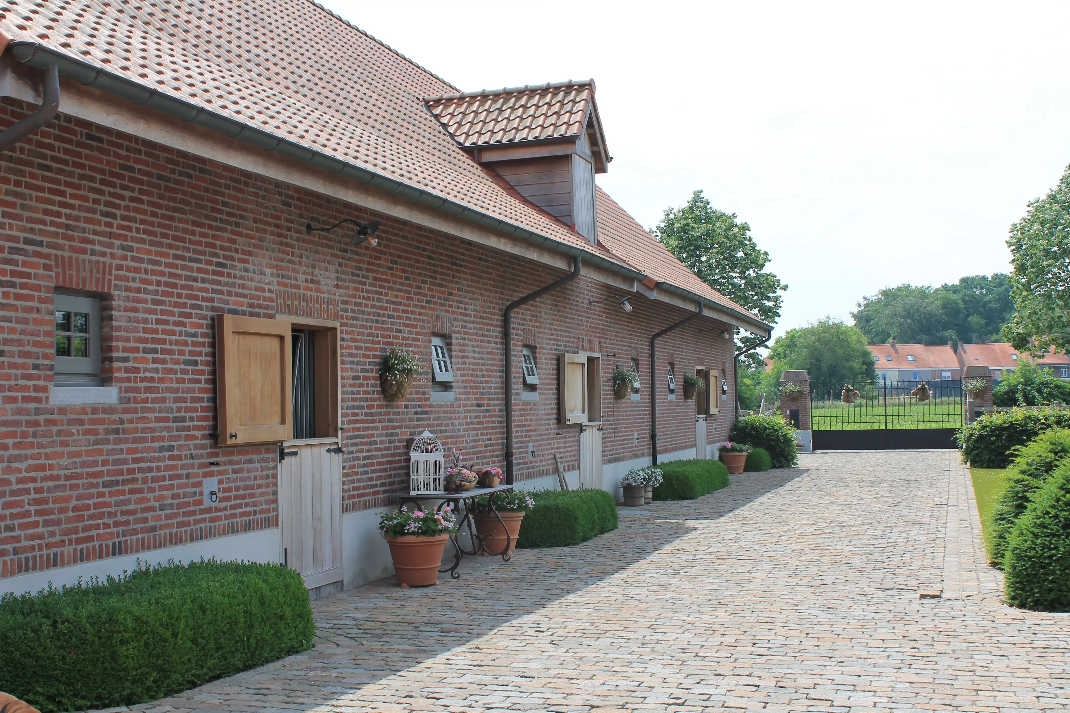 Het stalgebouw met verzorgde kasseien-oprit